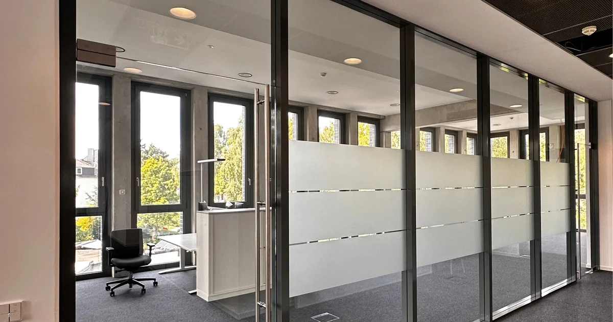 Bürogang mit verglasten Räumen, deren Glaswände mit Milchglas-Streifenfolie beklebt sind