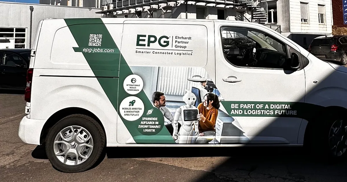 Weißer Kastenwagen mit grün-weißer Teilfolierung, Fotodruck, QR-Code und Werbeclaim auf der Seitenwand