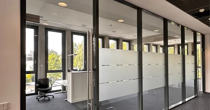 Bürogang mit verglasten Räumen, deren Glaswände mit Milchglas-Streifenfolie beklebt sind