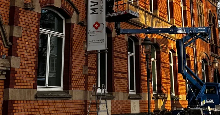 Grossformatig bedrucktes Werbebanner an einem Gebaeude, aufgenommen von der Strasse aus.