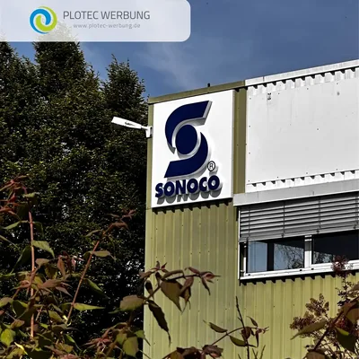 Sonoco-Logo an der Fassade einer Werkshalle, davor Bäume