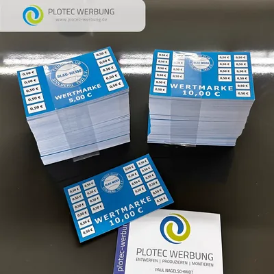 Stapel blauer Wertmarken neben einer Visitenkarte von Plotec Werbung
