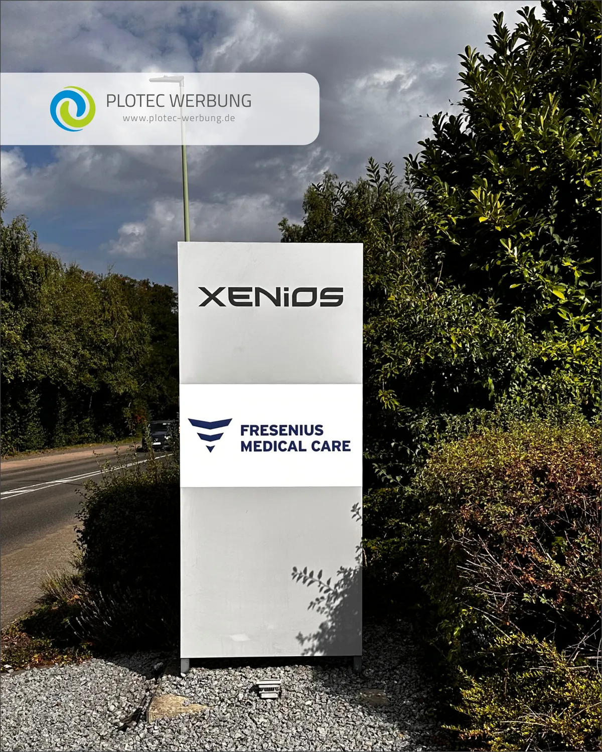 Xenios: Werbepylon mit mehreren Firmenlogos an der Zufahrt